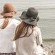 two women wearing sun hats look at the water