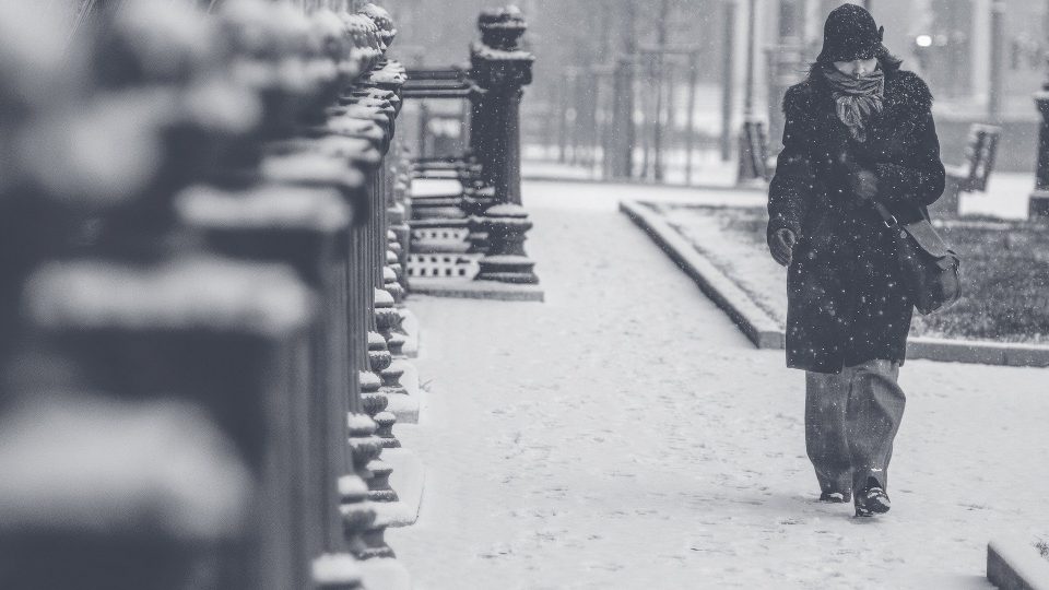 woman walking down a city street during a very cold and snowy day